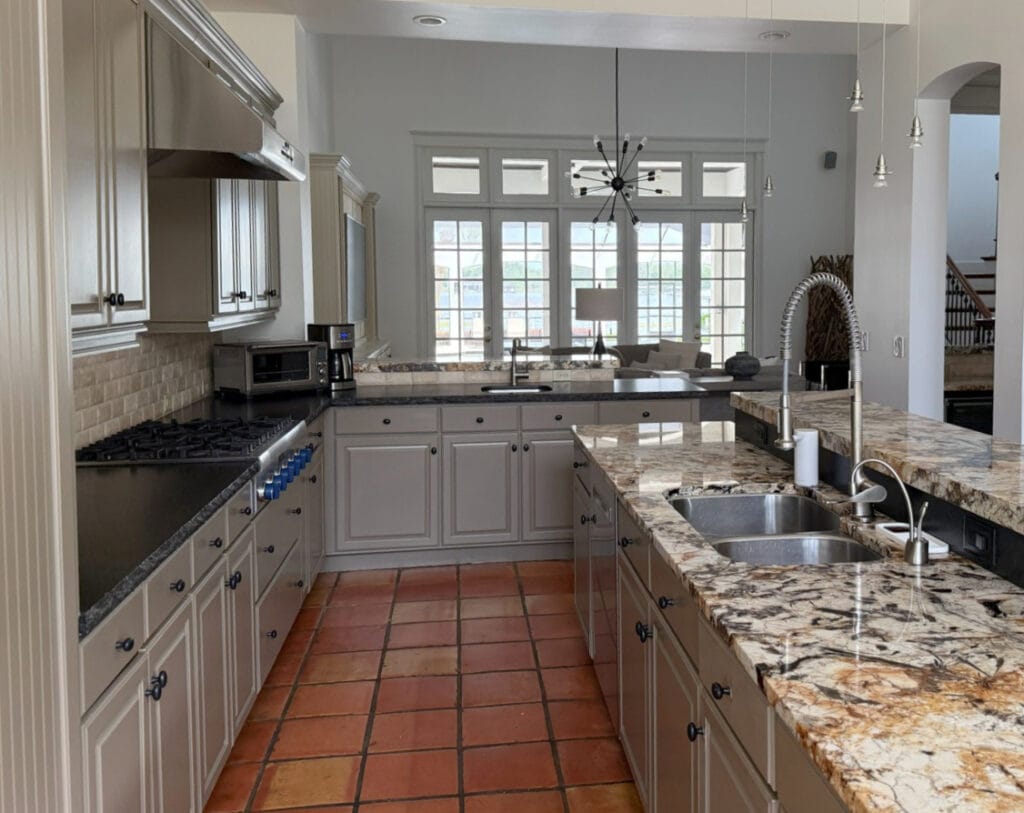 Gold and cream granite countertop (2000s) Spanish or mexican tile floor (terracotta), black granite, greige-green painted cabinets, update ideas