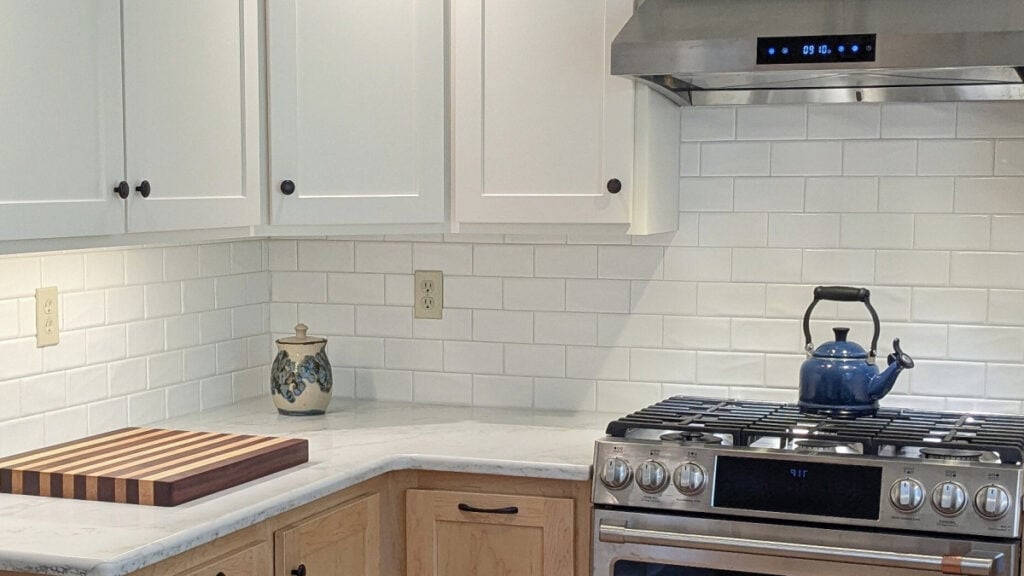 Sherwin Williams Alabaster, warm white kitchen abinets with subway tile, quartz, and light wood lower cabinets