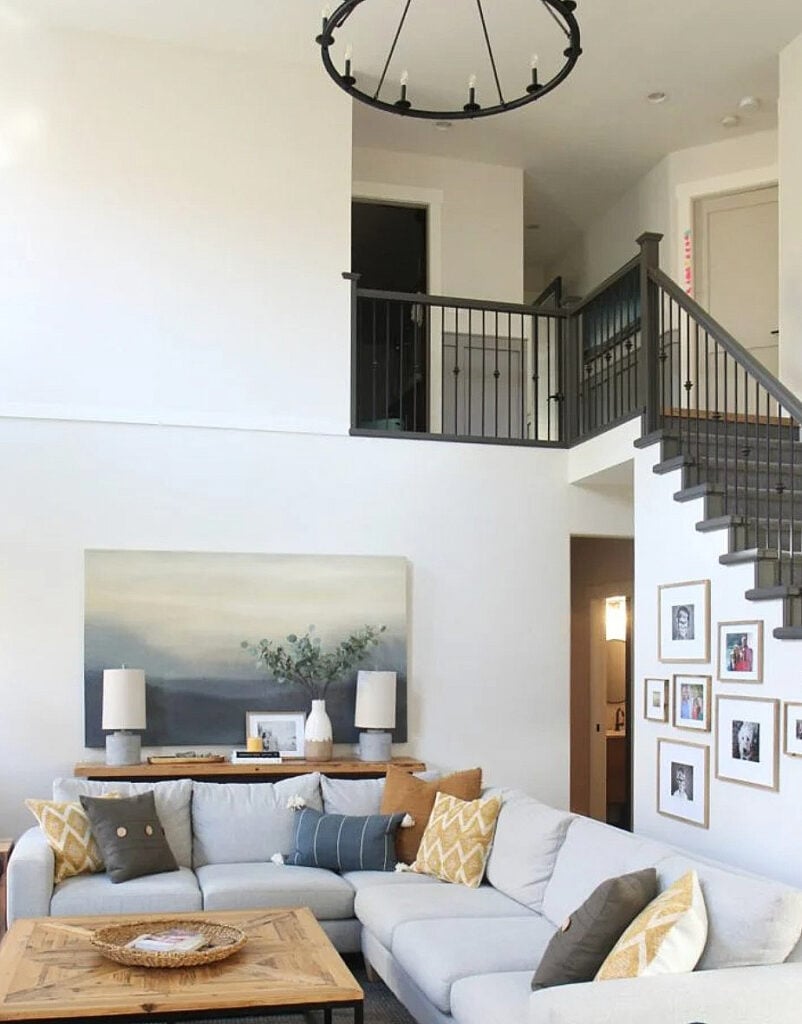 living room with a vaulted, high ceiling, round chandelier, gray sectional and white walls - north facing