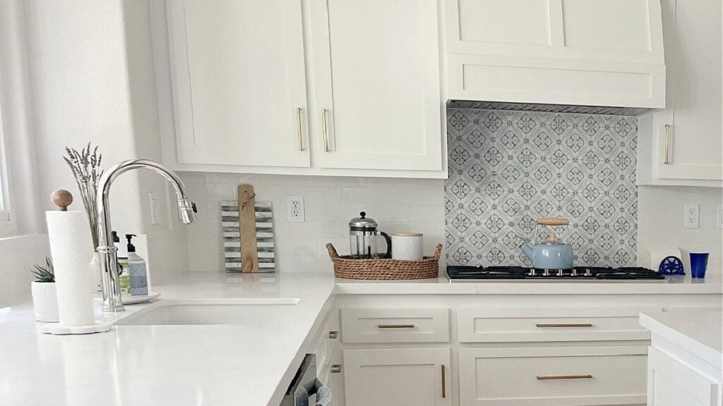 Kitchen with Sherwin Williams PUre White cabinets, blue patterned accent tile, white subvway, quartz countertop and home decor