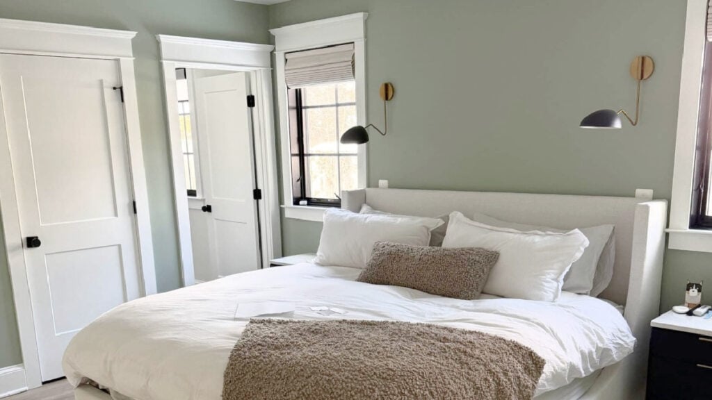 Benjamin Moore Cascade Green paint color, looks like a sage green in bedroom with neutral linens and upholstered bed, north-facing exposure