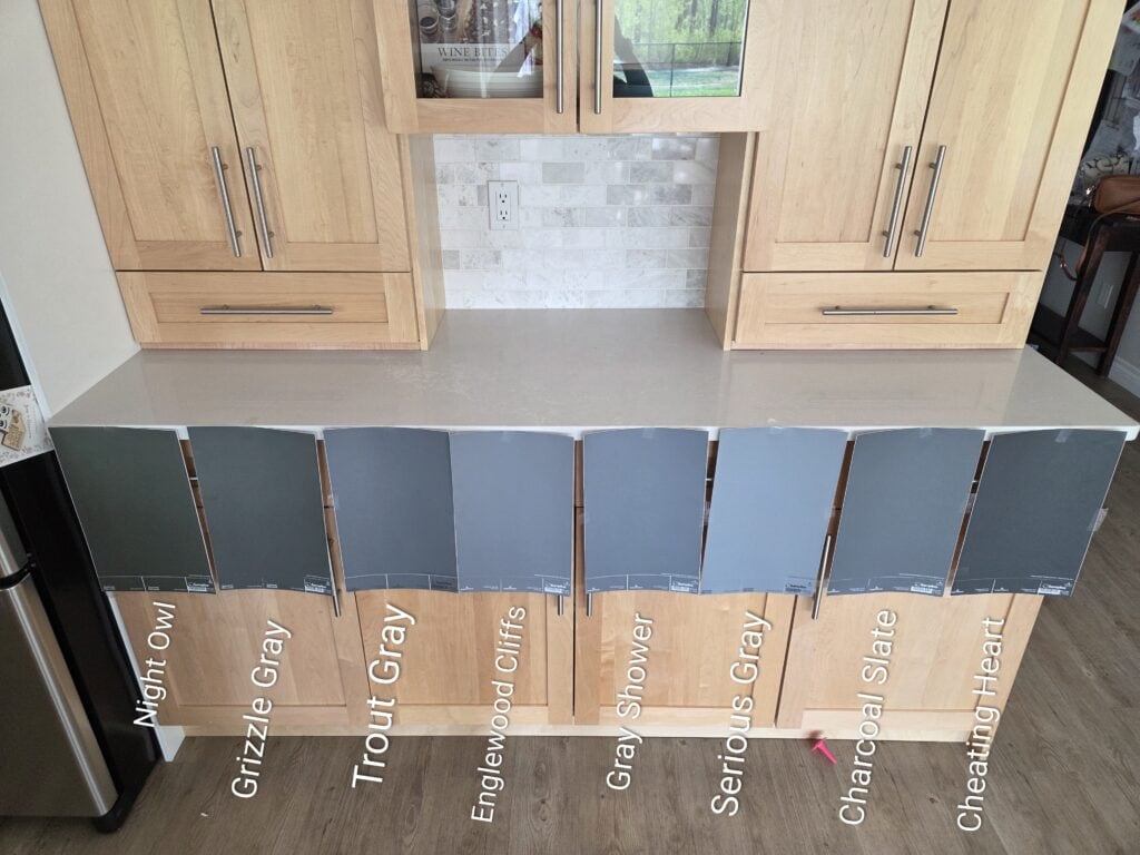 Benjamin Moore dark blue-grays like Charcoal Slate, Cheating Heart, and sherwin williams green grays like Grizzle Gray and Night Owl with gray quartz and maple cabinets