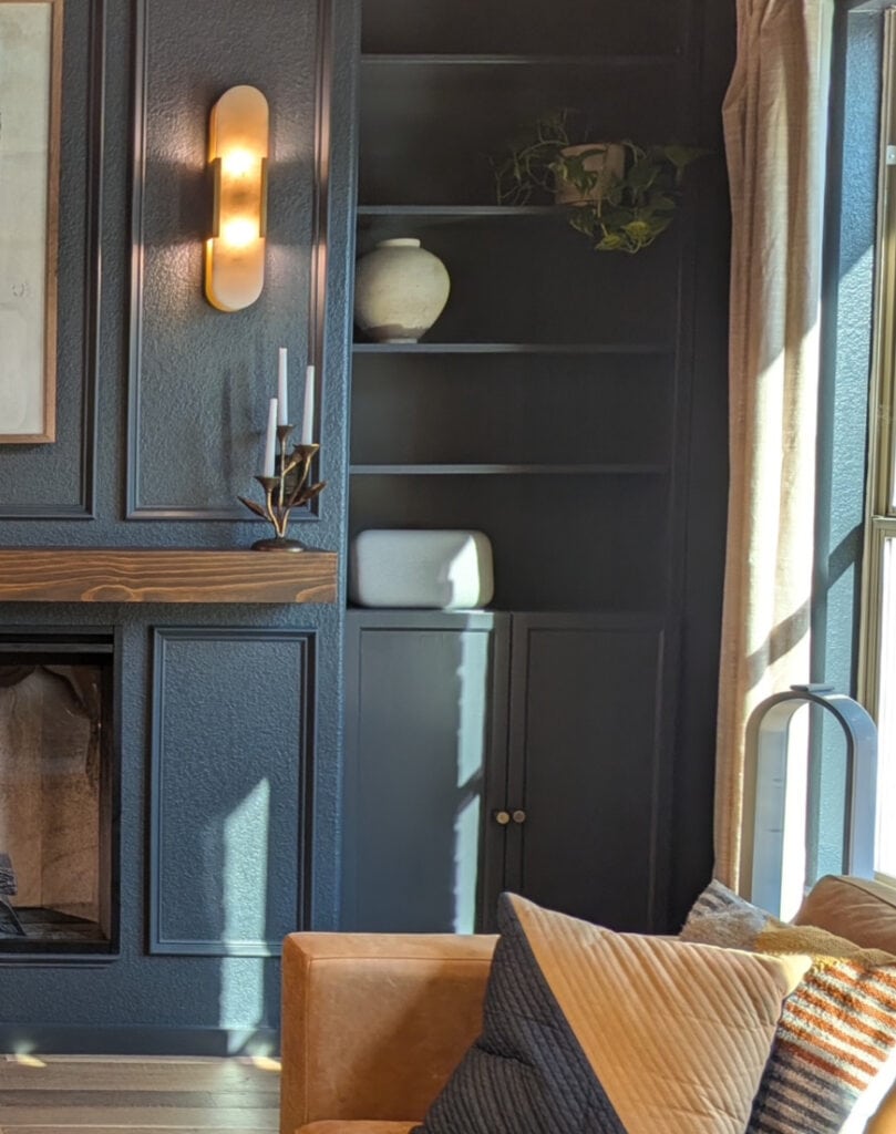 Sherwin Williams Cyberspace, dark blue in moody cigar, wine room or den with built-ins and dark wood stained mantel, wall sconces
