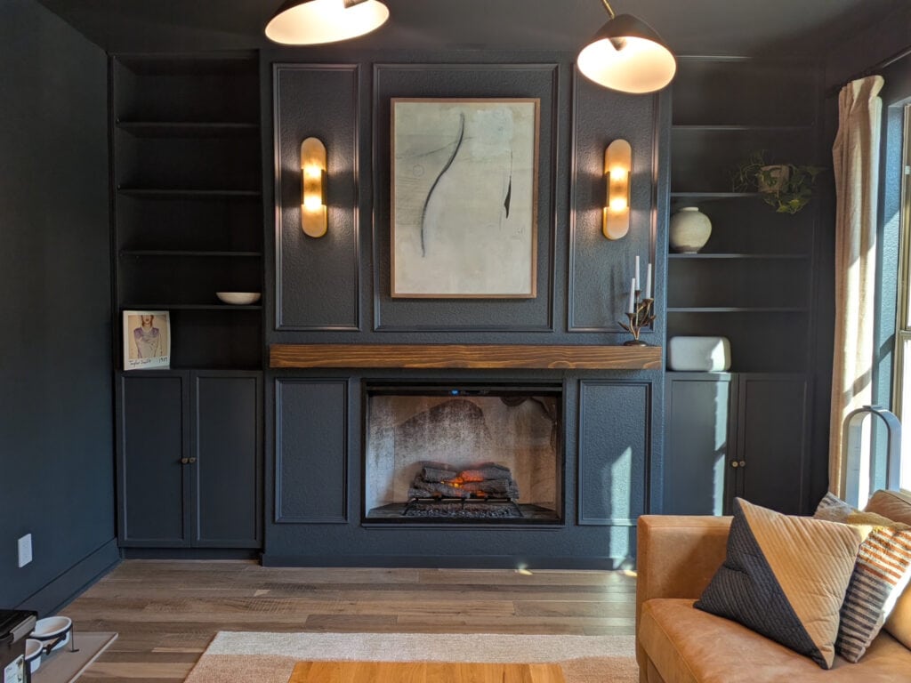 Sherwin Williams Cyberspace in moody dark blue den, cigar room, library. Natural light, dark stained wood mantel, gas fireplace, built-ins, moldings and color drenched walls with wood floor.