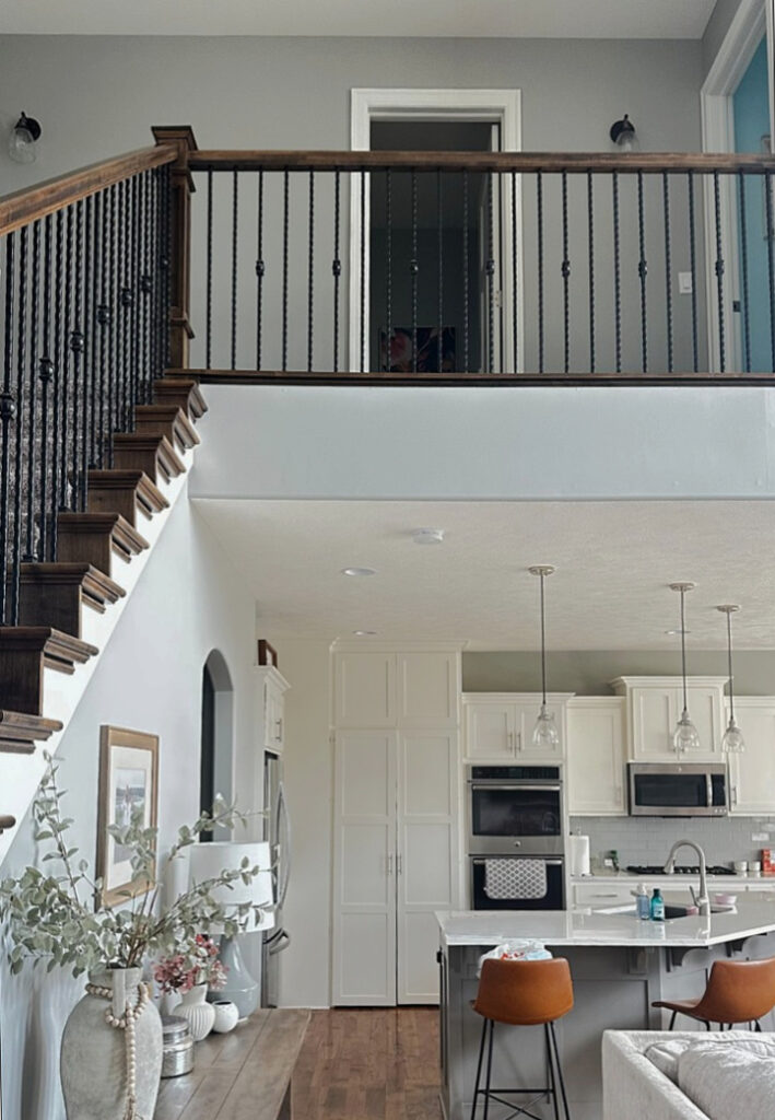 Sherwin Williams Mindful Gray, southwest facing exposure with white kitchen and wood hand railing on stairs.