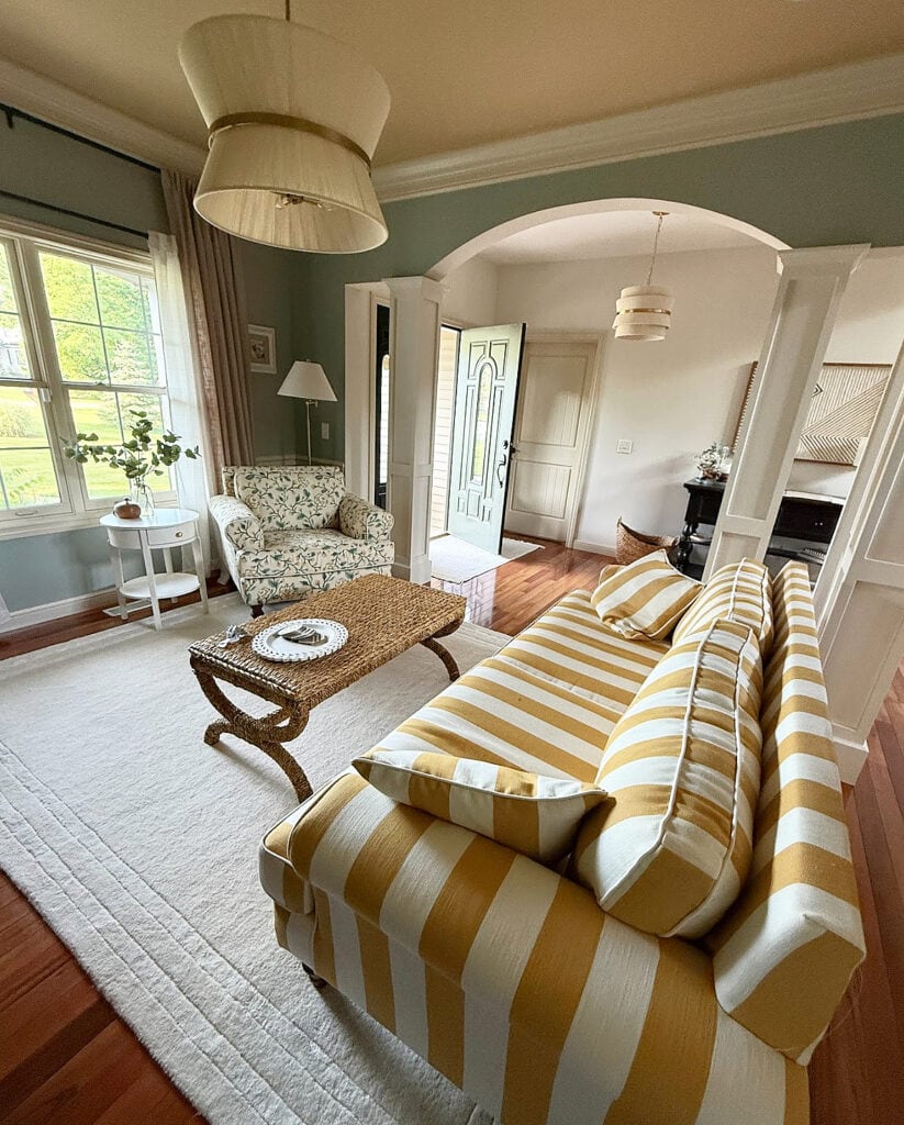 Sherwin Williams Oyster Bay (green-gray) walls with Softer tan trim and darker beige ceiling, gold striped sofa, crown molding, sitting room.
