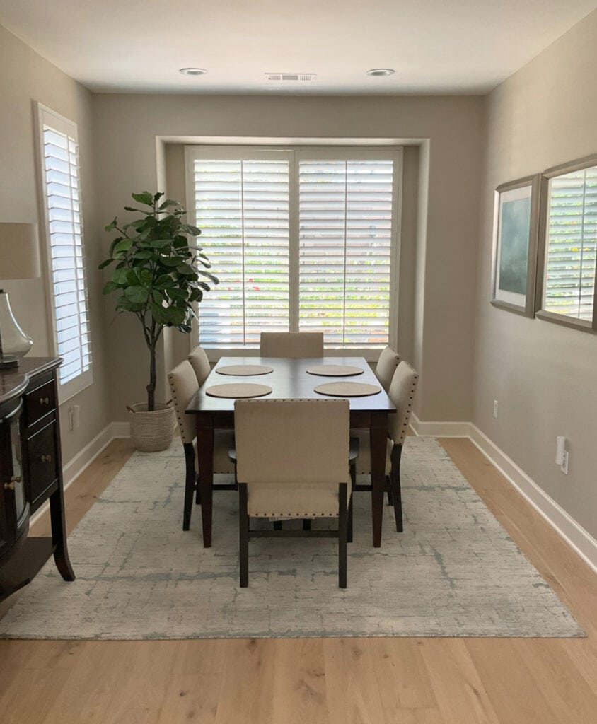 Dining room with natural light, dark wood furniture and light oak wood flooring. Sherwin Williams Accessible Beige walls