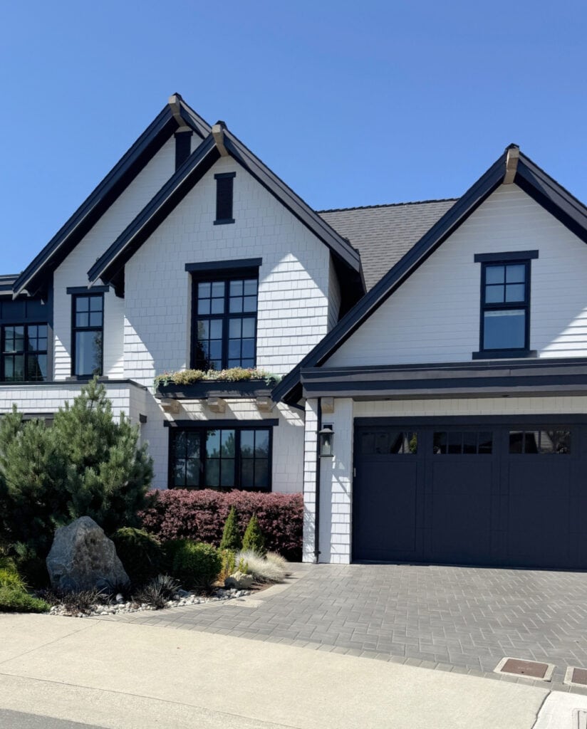 James Hardie Arctic White exterior siding and shakes with dark blue-black trim, fasica, garage doors, black windows and gutters