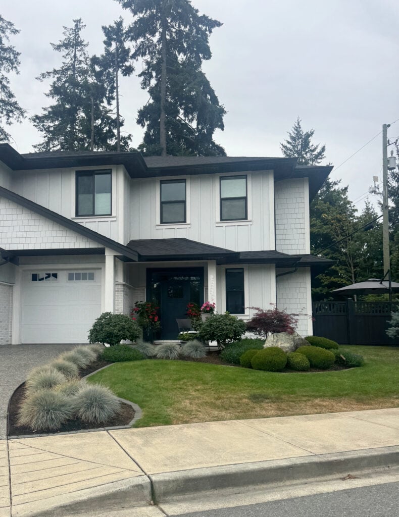James Hardie Arctic White exterior siding, board and batten and white trim with black windows and gutters. north-east-facing exposure on cloudy day