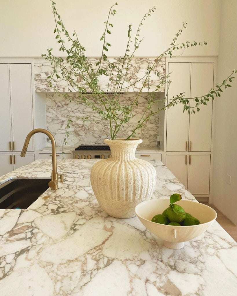 Sherwin Williams Alabaster lightened, warm marble kitchen countertop, slab backsplash and range hood. Flat panel cabinets. Gold hardware, Baldwin Homes