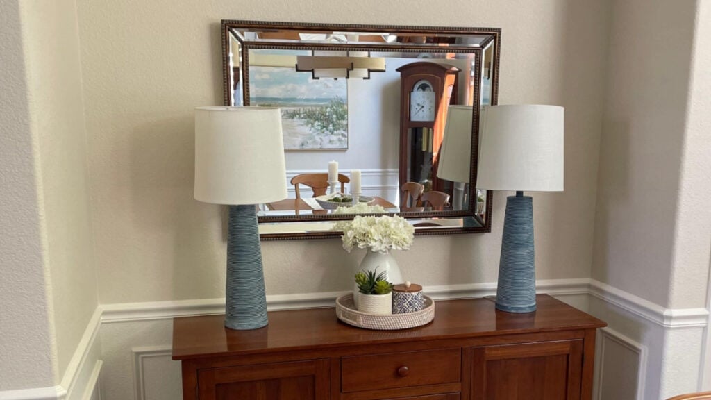 Sherwin Williams Natural LInen beige walls with blue lamps and cherry red buffet. Moderate White lightented trim