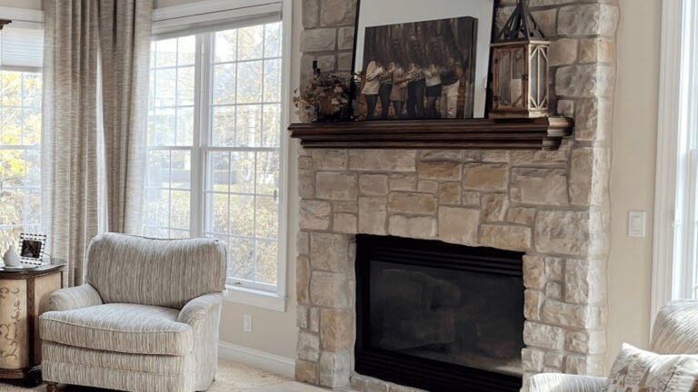 Stone fireplace from early 2000s with beige tones and accent chair